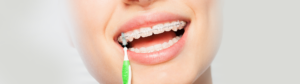 Woman using interdental brush to clean braces.